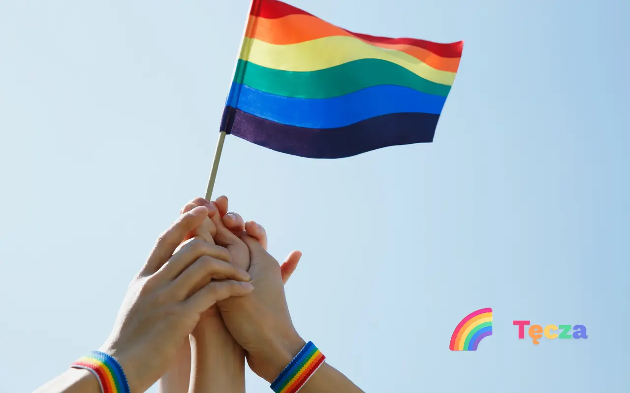 Osoby trzymające flagę tęczy z napisem 'Tęcza.app'